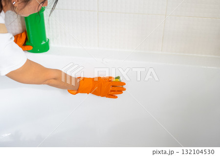 Hands in rubber gloves close-up and bottle of detergent is in bathroom of house with sponge cleaner and cleaning agent on bath. Restoring order, cleanliness and hygiene in home, cleaning servise 132104530