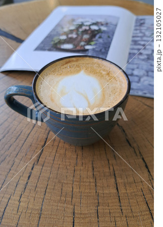 A cup of coffee with milk or cappuccino on a wooden table against the background of a modern cafe A cup of coffee with milk or cappuccino on a wooden table against the background of a modern cafe 132105027