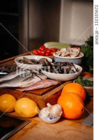 Sea bream, garlic, shrimp and shells on the table next to vegetables and fruit. Sea bream, garlic, shrimp and shells on the table next to vegetables and fruit. 132105672