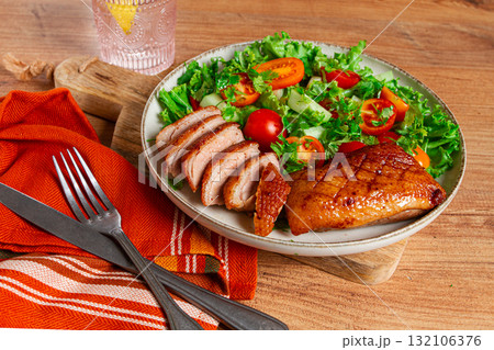 Delicious grilled duck breast served with fresh garden salad and cherry tomatoes at a rustic dining table Delicious grilled duck breast served with fresh garden salad and cherry tomatoes at a rustic dining table 132106376