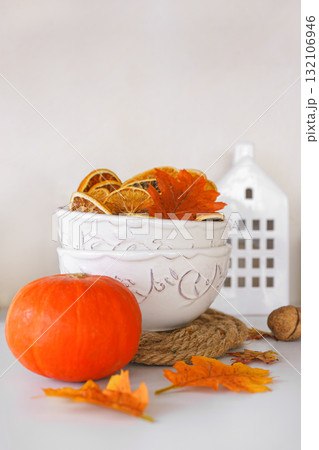 Autumn decoration with dried oranges, leaves, orange pumpkin in kitchen setting on white background 132106946