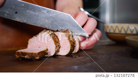 Chef Cuts Juicy Pork Steak on Rustic Cutting Board on Wooden Background Chef Cuts Juicy Pork Steak on Rustic Cutting Board on Wooden Background 132107278