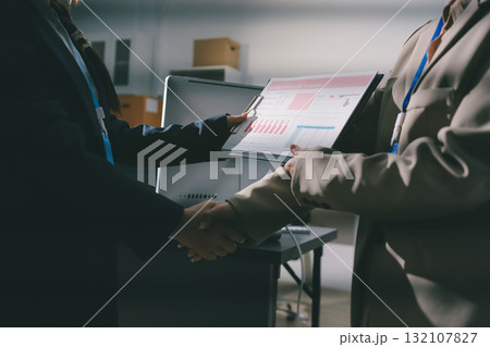 Business people shaking hands in office. Two business partners shaking hands after signing a contract in office. 132107827