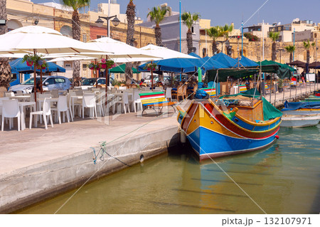 Colorful luzzu boat on Marsaxlokk promenade, Malta Colorful luzzu boat on Marsaxlokk promenade, Malta 132107971