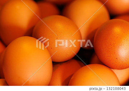 Fresh brown eggs piled together on a rustic surface in a warm, inviting kitchen setting 132108043