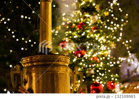 Warm glow from a decorative heater near a beautifully lit Christmas tree with festive ornaments at night Warm glow from a decorative heater near a beautifully lit Christmas tree with festive ornaments at night 132108065