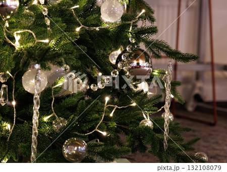 Beautifully decorated Christmas tree adorned with shiny ornaments and warm lights glowing in a cozy room Beautifully decorated Christmas tree adorned with shiny ornaments and warm lights glowing in a cozy room 132108079