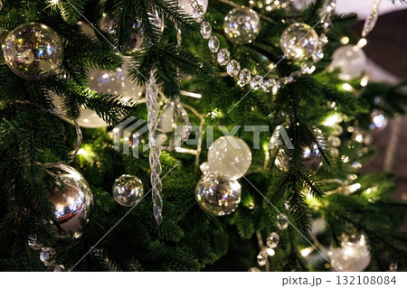 Sparkling ornaments and lights decorate a festive Christmas tree in a cozy indoor setting during the holiday season Sparkling ornaments and lights decorate a festive Christmas tree in a cozy indoor setting during the holiday season 132108084