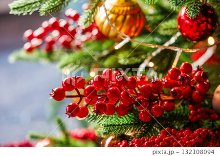 Festive holiday decorations showcasing bright red berries and sparkling ornaments on a Christmas tree 132108094