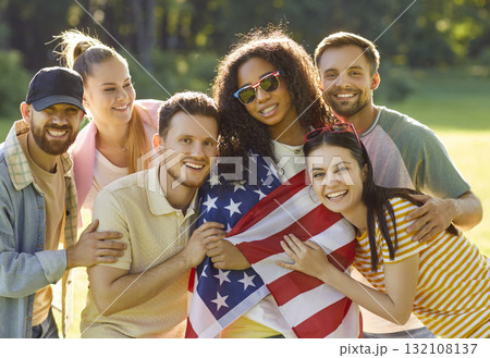 Patriotic cheerful friends posing together, wrapped in USA flag, celebrate America Independence Day Patriotic cheerful friends posing together, wrapped in USA flag, celebrate America Independence Day 132108137
