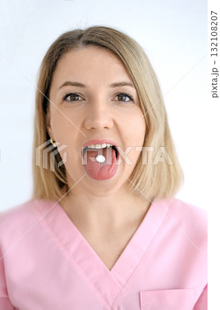 Portrait of a woman holding a pill on her tongue. The danger of using medications without a doctor's prescription 132108207