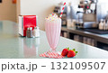Pink Milkshake With Sprinkles and Straw on a Diner Counter with Fresh Strawberries 132109507