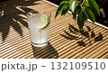 Refreshing Cocktail With Lime Slice And Ice Cubes On Bamboo Table With Green Leaf Shadow 132109510