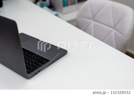 Laptop, workspace, desk. Modern dark grey notebook computer open on a clean white table with copy space 132109532