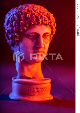 Close-Up of Plaster Hermes Bust with Colorful Neon Backdrop 132109627