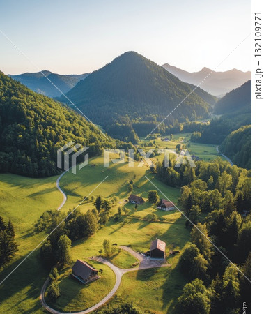 Aerial View Of A Lush Green Valley At Sunset With Rolling Hills Houses And Forest Paths Illuminated By Golden Light 132109771