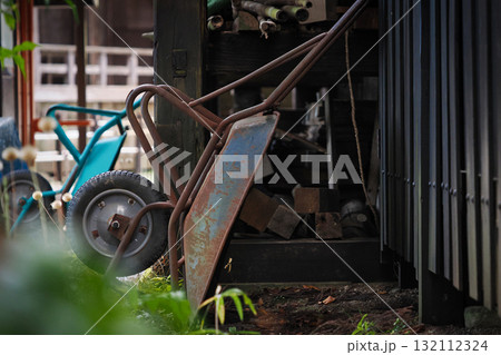 倉庫の壁に立てかけられた古い手押し車 倉庫の壁に立てかけられた古い手押し車 132112324