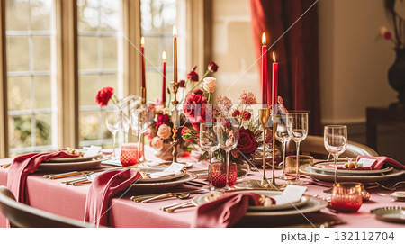Festive table setting with cutlery, candles and beautiful red flowers in a vase. 132112704