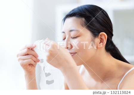 フェイスパックを手に取っている女性 フェイスパックを手に取っている女性 132113024