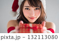 クリスマスプレゼントを差し出すサンタクロースの衣装を着た女性 132113080