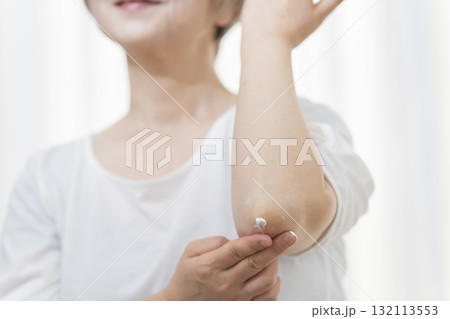 肘のカサつきにクリームを塗るシニア女性 肘のカサつきにクリームを塗るシニア女性 132113553
