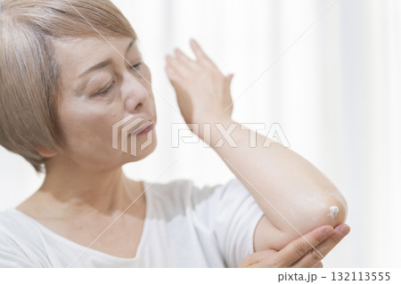 肘のカサつきにクリームを塗るシニア女性 132113555