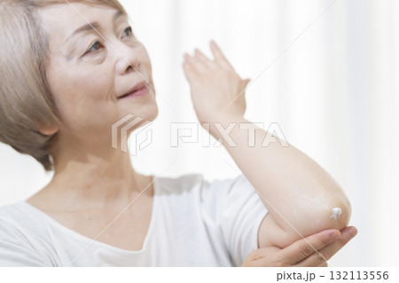 肘のカサつきにクリームを塗るシニア女性 肘のカサつきにクリームを塗るシニア女性 132113556