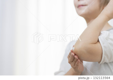 肘のカサつきにクリームを塗るシニア女性 132113564