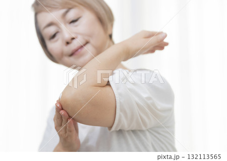 肘のカサつきにクリームを塗るシニア女性 肘のカサつきにクリームを塗るシニア女性 132113565