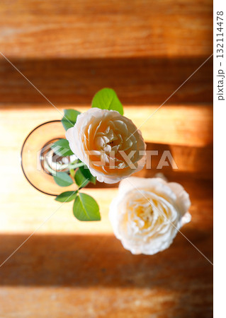 Yellow beautiful blooming rose in glass vase under window light on wooden table. Yellow beautiful blooming rose in glass vase under window light on wooden table. 132114478