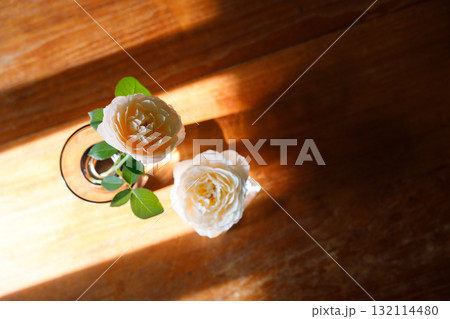 Yellow beautiful blooming rose in glass vase under window light on wooden table. Yellow beautiful blooming rose in glass vase under window light on wooden table. 132114480