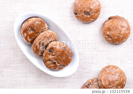 Fruit gingerbread, traditional German Lebkuchen in a white bowl, on linen. Christmas spice cookies, with candied fruit pieces, sugar glazed, dipped in dark chocolate at the bottom. Photo 132115539