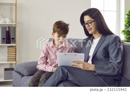 School counselor, therapist or psychologist discussing something with little boy School counselor, therapist or psychologist discussing something with little boy 132115942