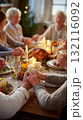 Family gathered around a festive dinner table holding hands in gratitude by candlelight 132116092