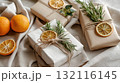 Beautifully wrapped gifts decorated with dried oranges, rosemary, and twine on linen fabric. The image conveys natural style, handmade creativity, and eco-friendly holiday aesthetics 132116145