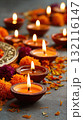 Traditional clay oil lamps burning brightly among colorful flower petals on a festive background 132116147
