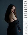 Elegant woman posing with confidence against a dark backdrop in a studio setting 132117573
