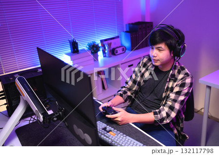 Focused gamer playing video game at night time 132117798
