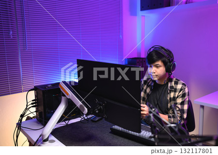 Focused gamer playing video game at night time 132117801