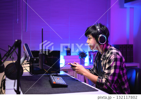 Focused gamer playing video game at night time 132117802