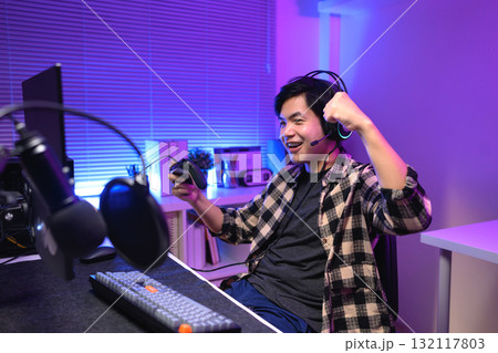 Excited gamer celebrating victory after winning video game at night, 132117803