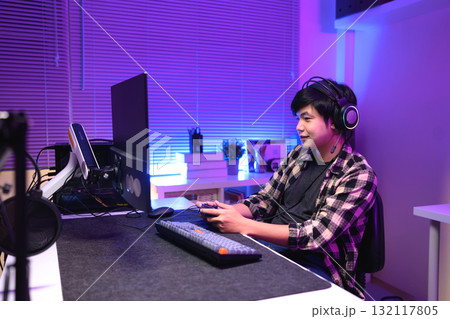 Focused gamer playing video game at night time 132117805