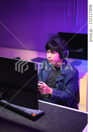 Focused gamer playing video game at night time 132117806