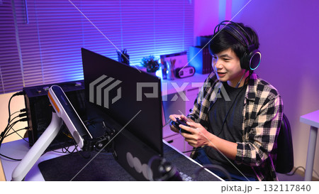 Focused gamer playing video game at night time 132117840