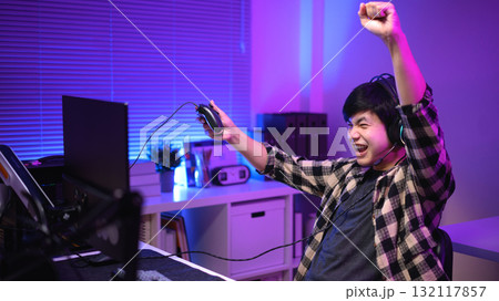 Excited gamer celebrating victory after winning video game at night, 132117857