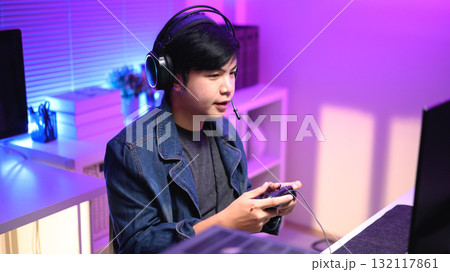 Focused gamer playing video game at night time 132117861