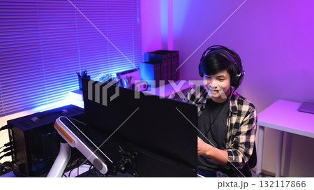 Focused gamer playing video game at night time 132117866