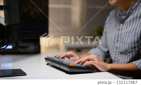 Cropped shot young man trader analyzing financial charts on computer at night, focused on investment strategy 132117867
