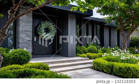 Modern house exterior showcasing a sleek black front door with a eucalyptus wreath. Featuring contemporary architecture. Stone cladding 132118303