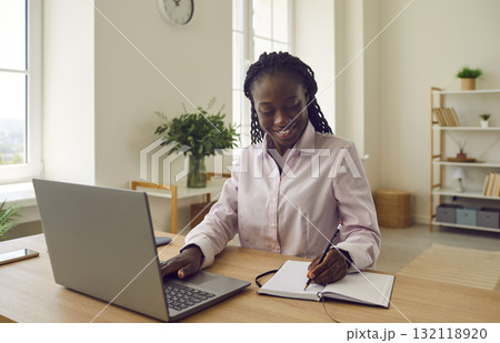 Happy African American businesswoman or college student using laptop and taking notes 132118920